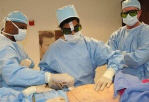 Doctor Pilay trains on liposuction as Dr. Reynolds and Dr. Miles observe and support.